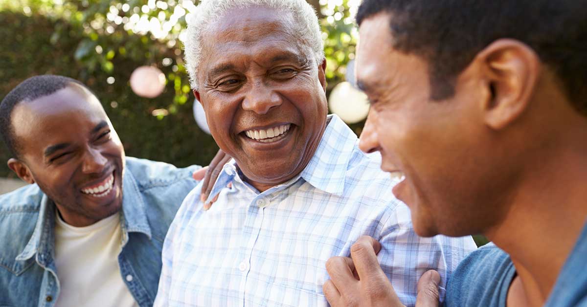 Senior man talking with his adult sons in garden