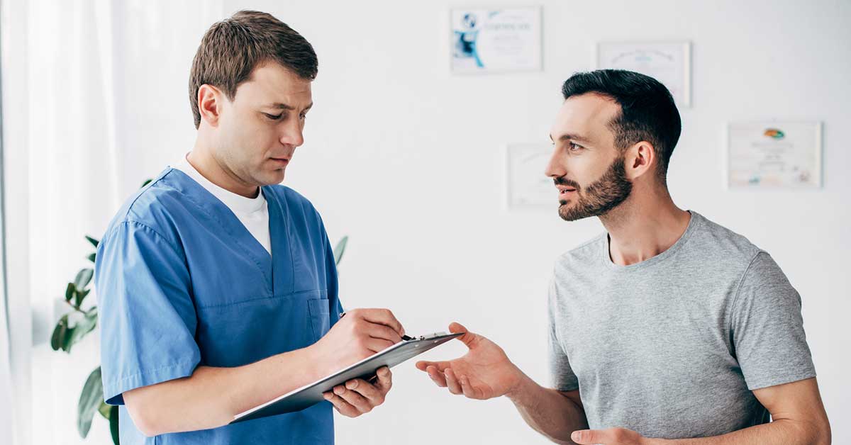 Patient sitting on couch and doctor writing prescription