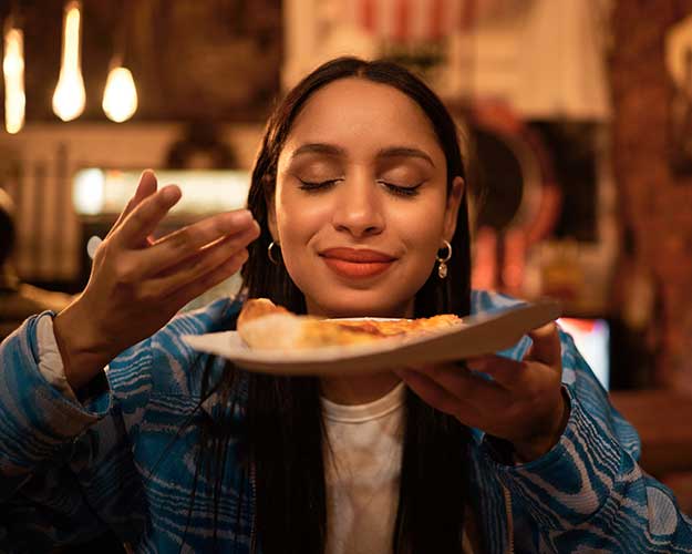 young woman smelling pizza