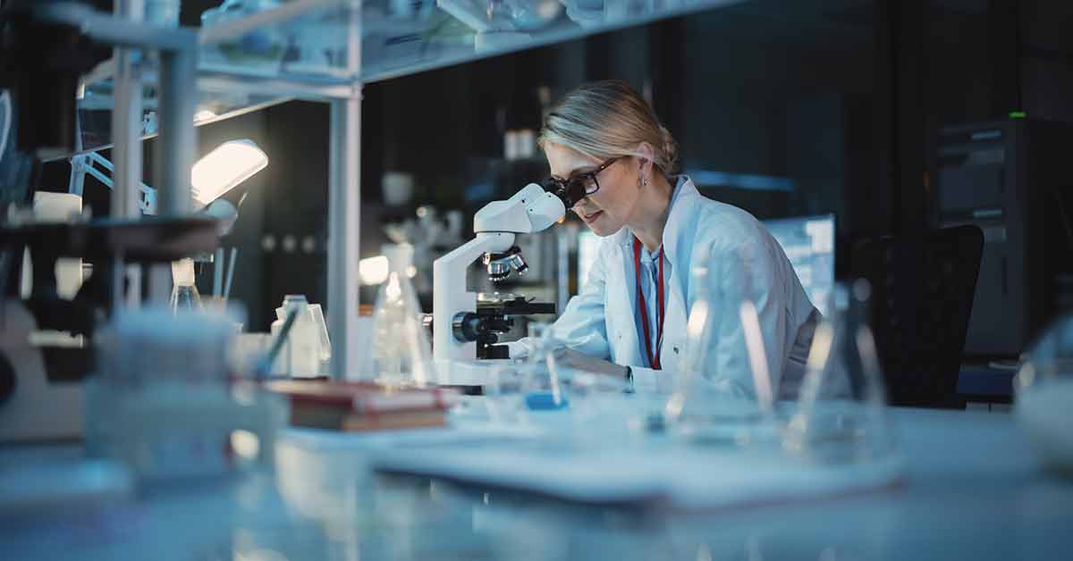 woman in lab looking into microscope