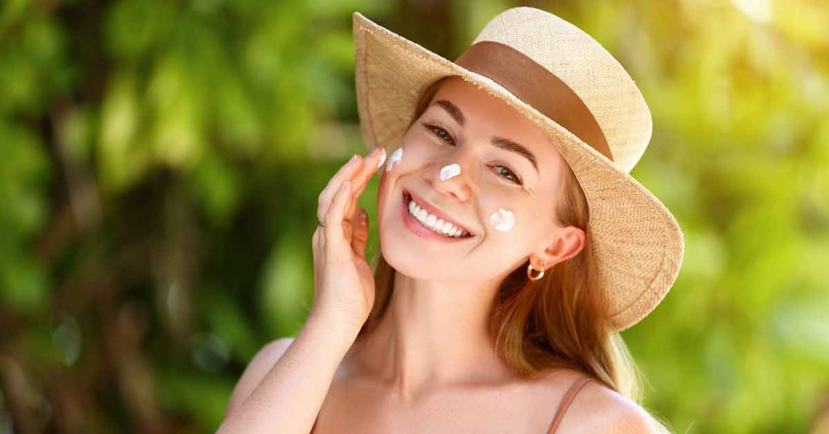 Woman in hat with sunscreen on nose and cheeks