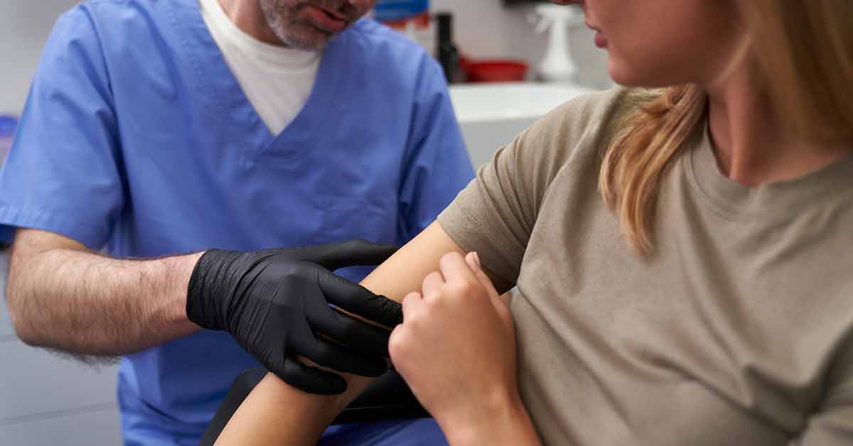 woman with light skin having skin mole examined by doctor