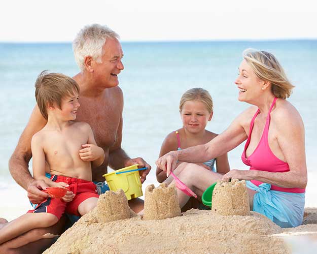 grandparents playing in sand with grand kids