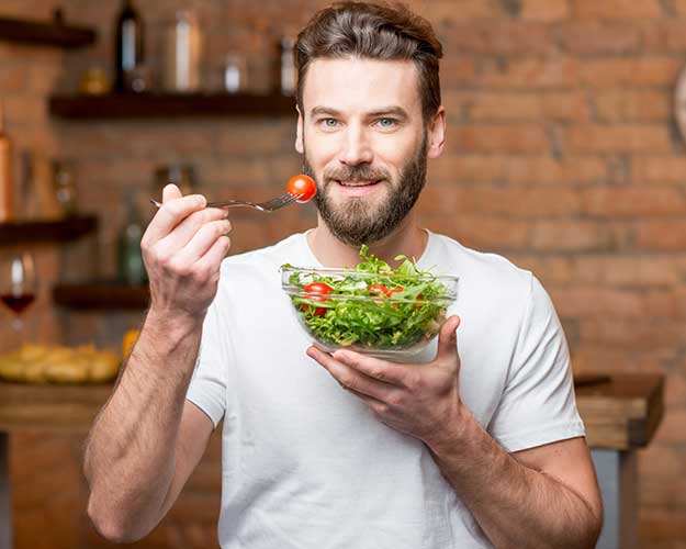 Mid aged man eating salad