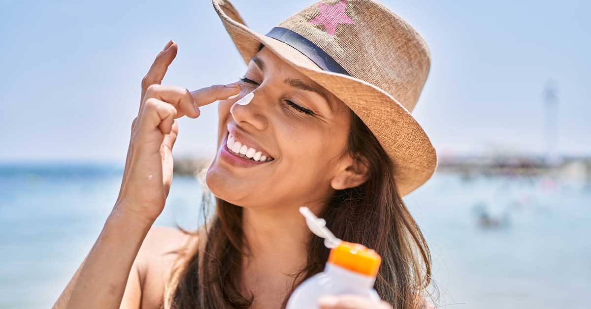 Woman in hat with sunscreen on nose